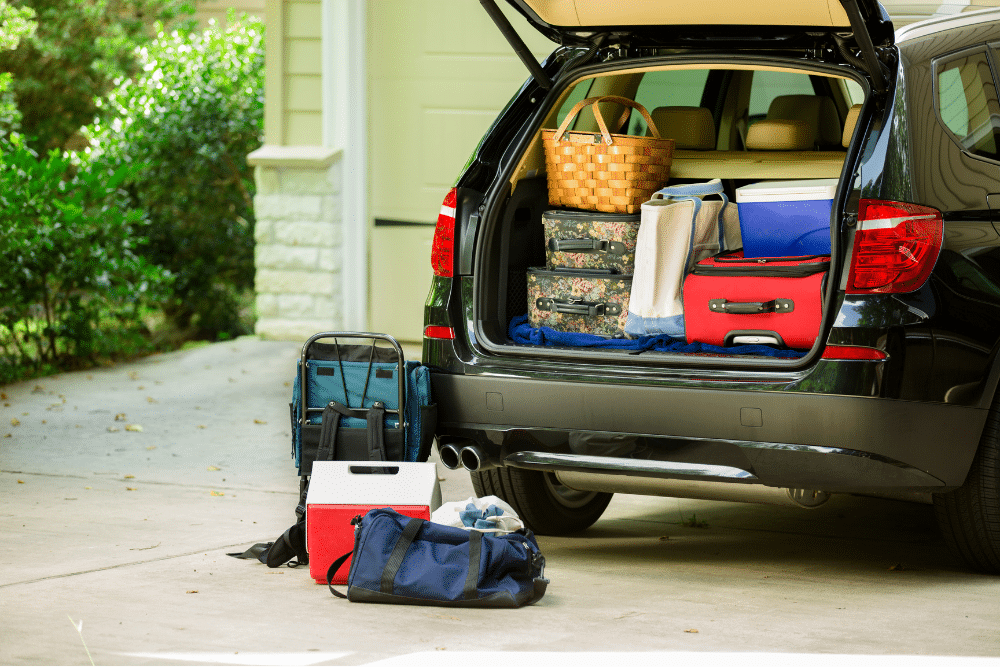 vehicle inspection. Auto repair in Patalaska, Tanzillo Automotive. SUV parked in a driveway with its trunk open and filled with various travel bags, suitcases, a picnic basket, and a cooler, indicating preparation for a road trip.