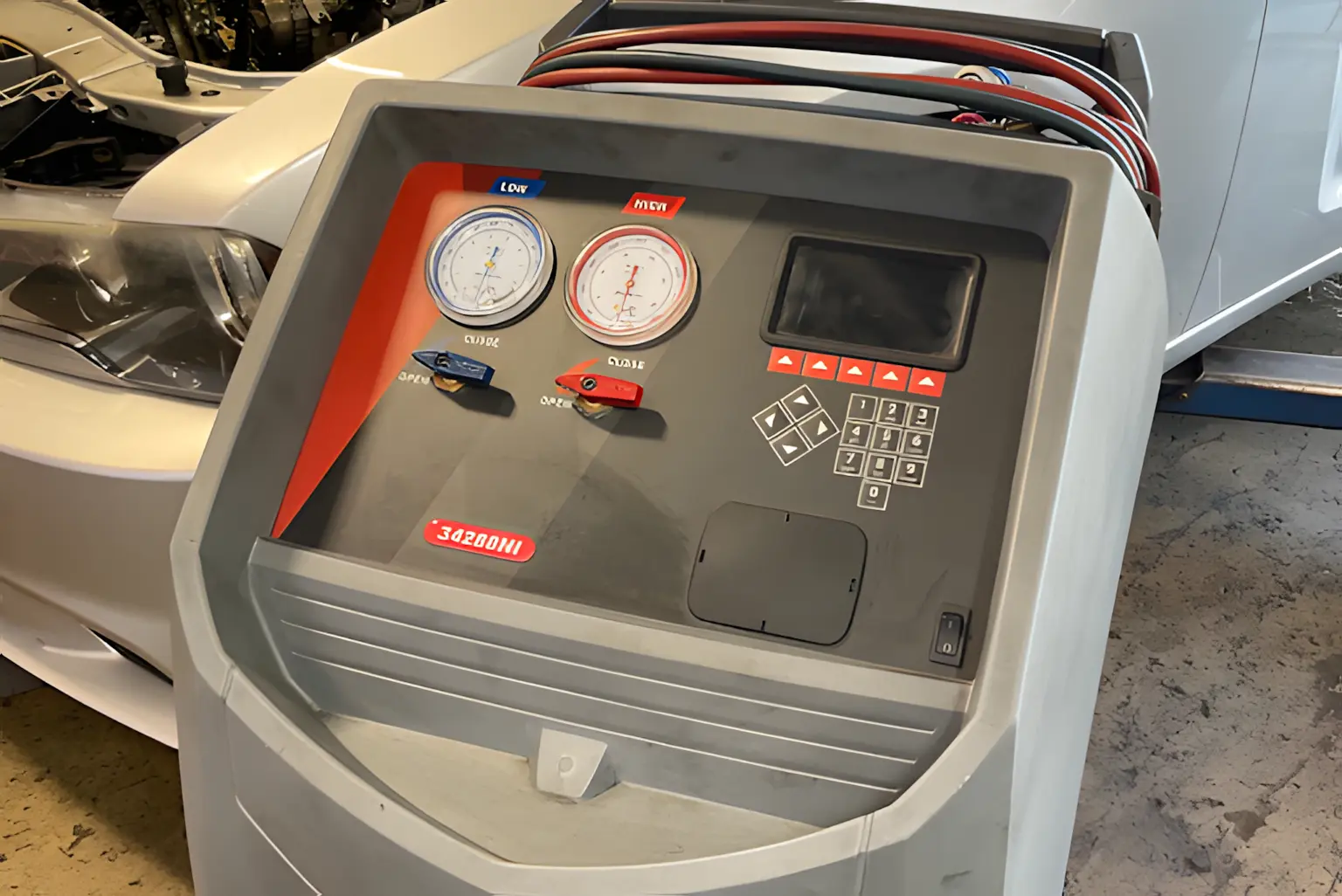 Image of an automotive A/C recharge machine with gauges and hoses connected, emphasizing professional air conditioning diagnostics and service for reliable cooling.