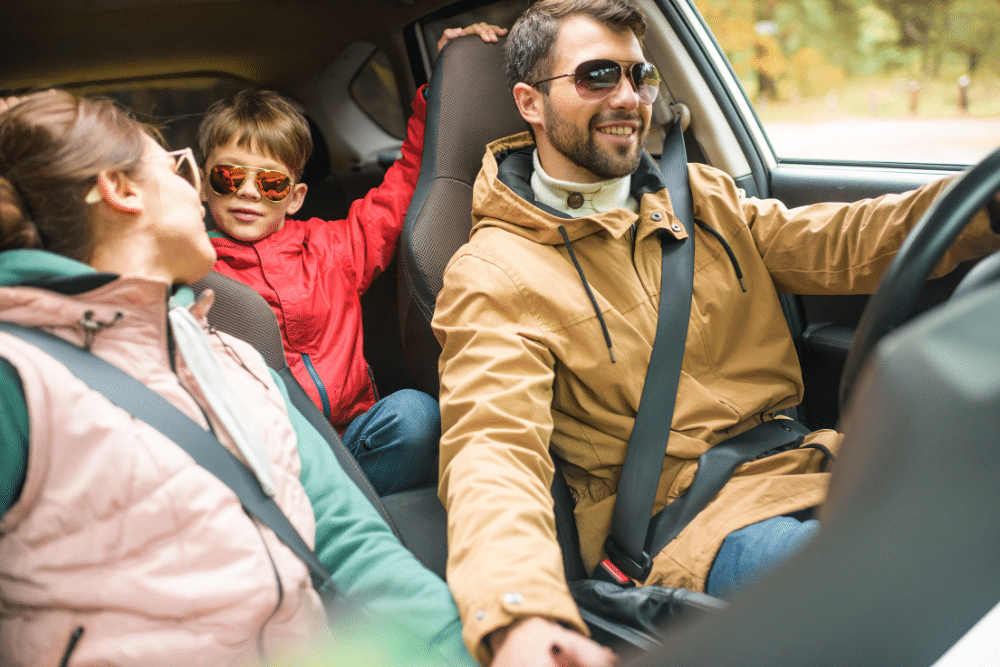 Car Maintenance Checklist, Auto repair in Palaska, OH. Image of a family riding together in a car, with a child wearing sunglasses in the backseat and parents smiling in the front, emphasizing the importance of vehicle inspections before travel.